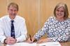 Alan Lewin and Julie Doyle sign the merger agreement